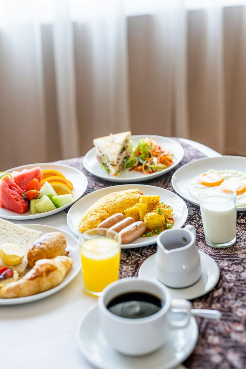 Mesa de café da manhã com frutas, pães, ovos, suco e café