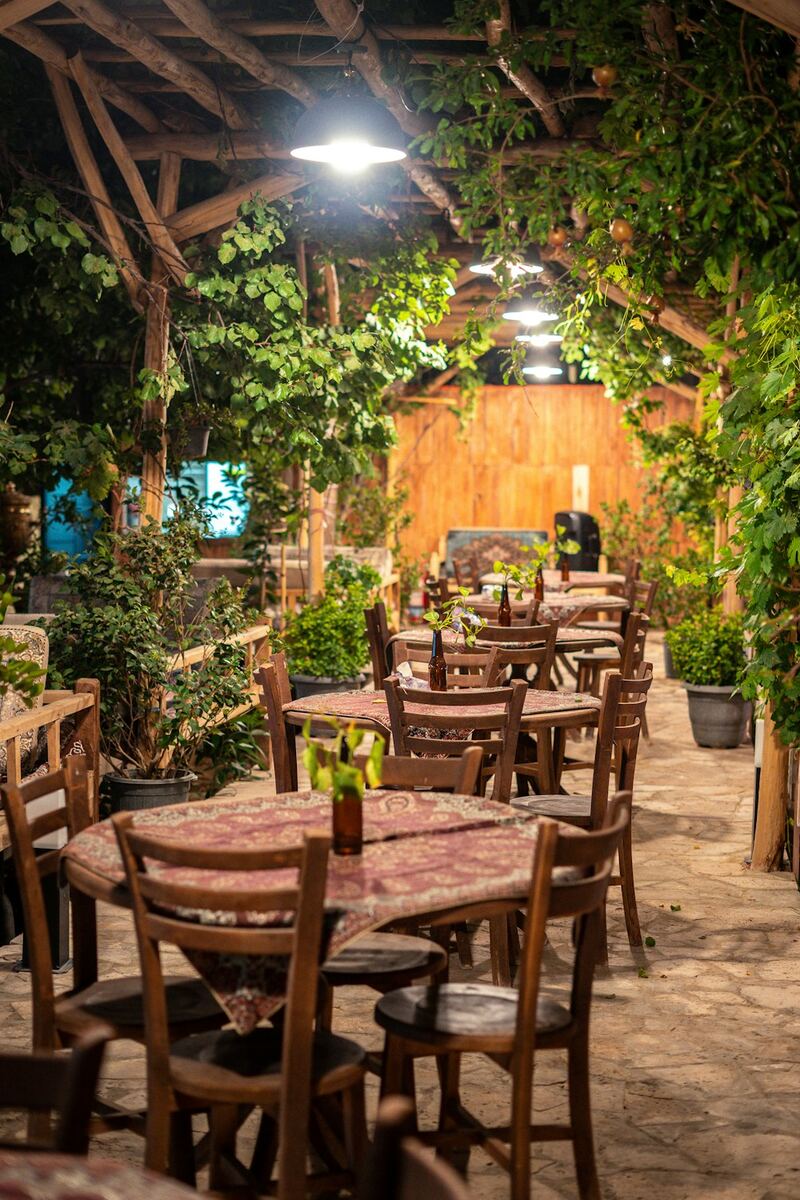 Restaurante ao ar livre sob pergolado coberto de plantas