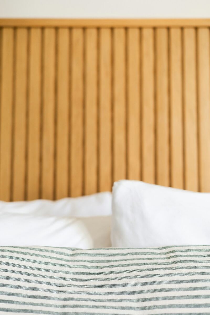 Detalhe da cama: travesseiros brancos e manta listrada