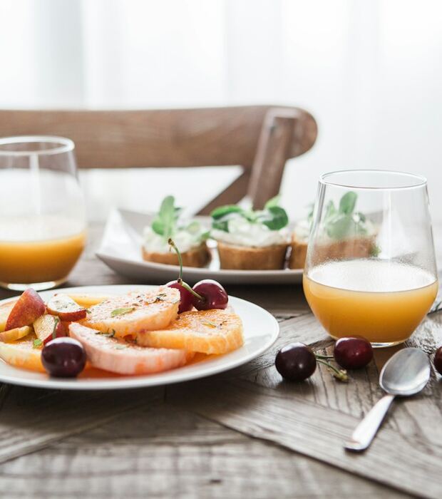 Café da manhã servido na mesa, com frutas, pães e suco