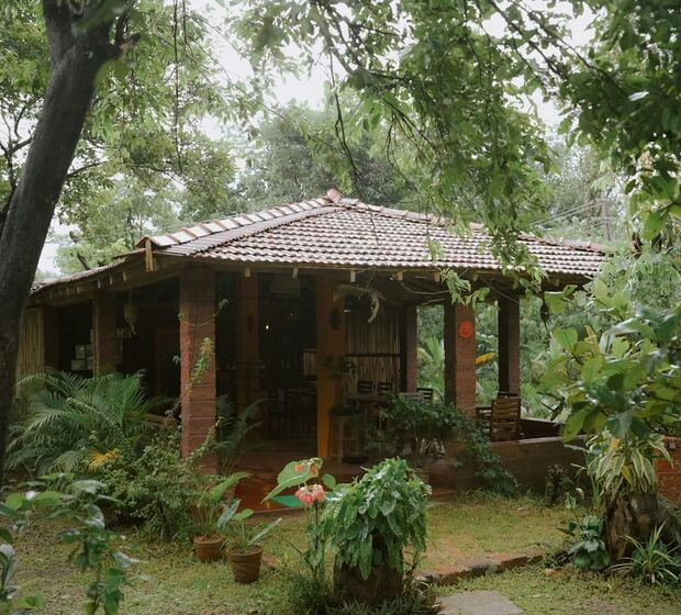Chalé da pousada com varanda, cercado por árvores e plantas